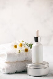 spa and wellness setting. composition with chamomile flowers and cosmetic bottle of essential oil serum and cream in zero waste package on white background