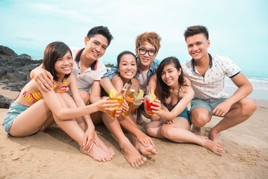 portrait of young people at beach toasting and looking at camera
