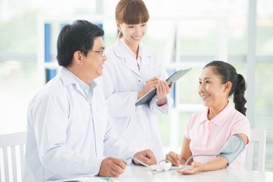 image of a doctor and his nurse checking up a senior patient in the clinic
