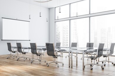 interior of modern office meeting room with white walls, wooden floor and glass conference table with black chairs and mock up projection screen. 3d rendering