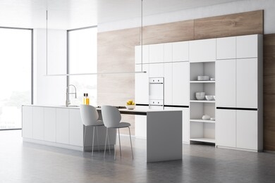 corner of stylish kitchen with wooden walls, concrete floor, white cupboards with built in ovens and white island with sink, cooker and chairs. 3d rendering