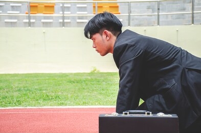 side view of asian business man ready to run on the lanes of a track