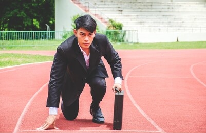 asian business man kneeling on the starting grid of a running track