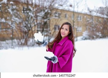 young asian woman wearing pink coat holding a snow with black leather gloves enjoying at winter park. happy asian girl christmas,new year concept