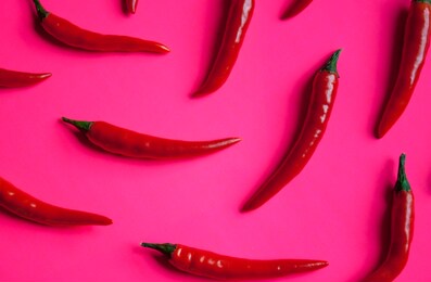 fresh red cayenne peppers on neon pink vibrant background.