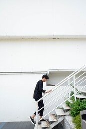 asian man walking up to white stair 