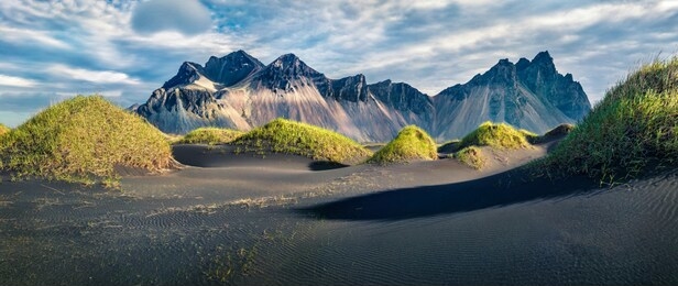 marvelous afternoon view of stokksnes cape with vestrahorn (batman mountain) on background. panoramic summer landscape with black sand dunes with green grass. travel to iceland.