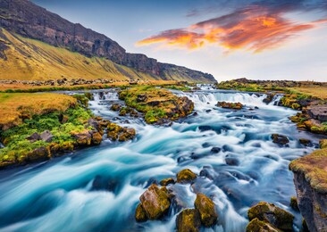 romantic summer view of small waterfall near bjodvegur road. impressive sunrise on iceland, vik location. beauty of nature concept background.