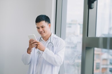 happy young doctor holding cell phone