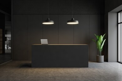 minimalistic office interior with dark gray walls, concrete floor, grey reception counter with laptop on it and stylish ceiling lamps. 3d rendering