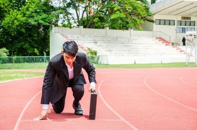 asian business man kneeling on the starting grid of a running track