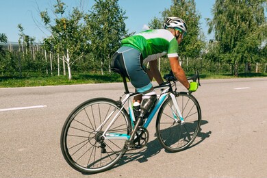 athlete with disabilities or amputee training in cycling in sunny summer's day. professional male sportsman with leg prosthesis practicing outdoors. disabled sport and healthy lifestyle concept.