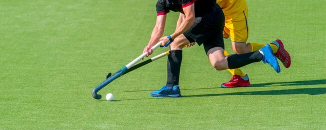 two field hockey player, fighting for the ball on the midfield during an intense match on artificial grass
