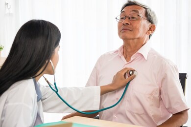 doctor listening to patient's heart rate with stethoscope in medical office