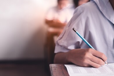 exam with uniform school student doing educational test with stress in classroom