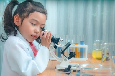 portrait of asian girl child in lab coat role playing being scientist in chemical lab