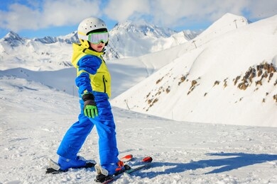 children's skiing in the mountains. toddler baby in a colorful suit and safety helmet. learning to ski. northern caucasus, georgia, gudauri