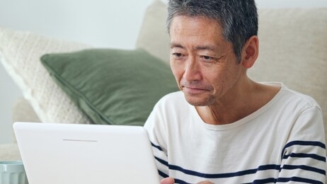 middle aged asian man using a laptop computer.