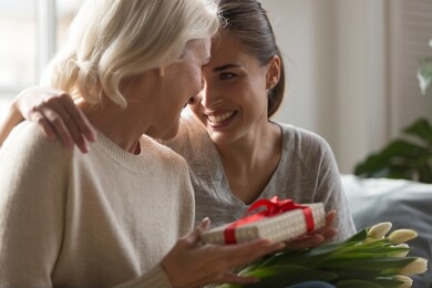 close up grown up loving daughter congratulates eight march or international women day middle aged mother giving her gift box spring flowers white tulips, life events, attention love and care concept