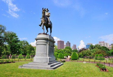george washington statue as the famous landmark in boston common park with city skyline and skyscrapers. 