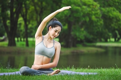 fitness asian woman doing yoga exercise and relax with sportswear in green park at summer, healthy lifestyle concept