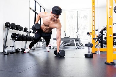 trainer men are teaching asian woman lifting a dumbbell. in the way they exercise in the gym.
