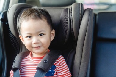 transport, safety, childhood road trip and people concept - happy baby boy sitting in baby car seat or booster seat, child in auto baby seat in car, asian boy in summer vacation to travel with family.