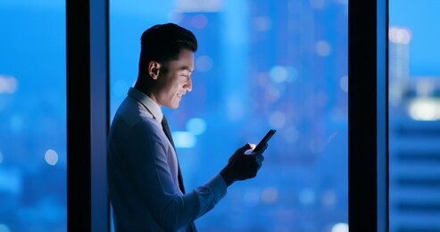 asian businessman use smart phone at night in the office
