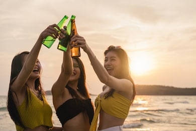 group of asian teenage girls having party celebrating on beach, friends happy drinking beer on beach at sea when sunset in evening. outdoor activity friends travel holiday vacation summer concept.