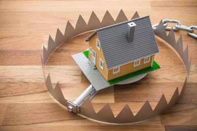 mortgage house in a bear trap on wooden table background. house trap on debt or loan problem or risk in real estate property financing concept.