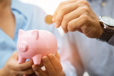 cheerful elderly couple saving money with putting coin into pigg