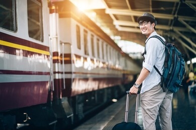 asian man is traveler, he is waiting for their train. outdoor adventure travel by train concept. bangkok, thailand. happy/positive/healthy hike/travel/wanderlust concept