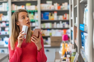 woman near counter in pharmacy drugstore. happy to decide. portrait of a happy pharmacy client holding a medication product. young woman choosing cosmetic cream in beauty shop.