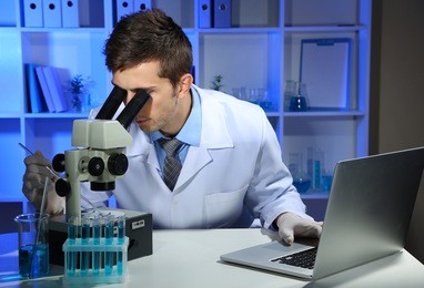 young laboratory scientist  looking at microscope in lab