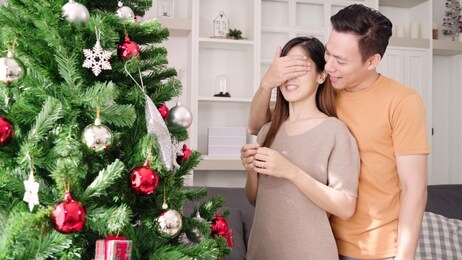 asian couple man giving christmas gifts to his girlfriend in their living room at home in christmas festival. lifestyle woman and man happy celebrate summer christmas and new year concept.