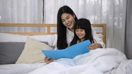 family concept. the mother is telling the story to her daughter before sleeping.