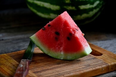 watermelon, sliced, knife, kitchen board on an old rustic table.