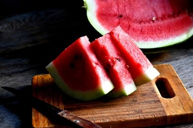 watermelon, sliced, knife, kitchen board on an old rustic table.