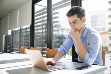 young asian male professional at desk smiling look at laptop business man concept.