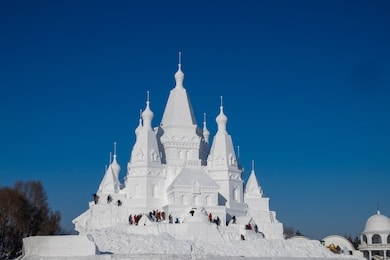 large snow castle under a clear blue sky during winter time in international snow festival, harbin, china