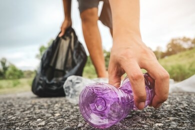 the volunteer picking up a bottle plastic in to a bin bag for cleaning, volunteering concept. environmental pollution and ecological problem.