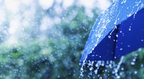 lifestyle scene of rainy weather. blue umbrella under rainfall. banner format.