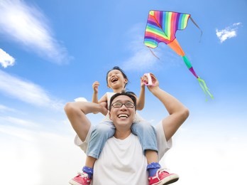 happy little girl on his father shoulder with colorful kite