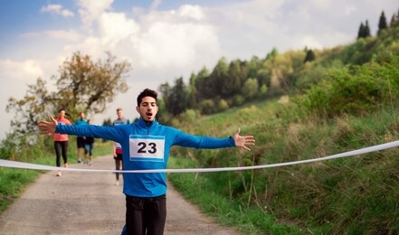 man runner crossing finish line in a race competition in nature.