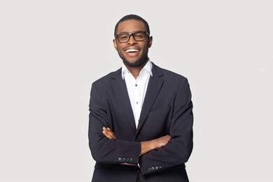 happy african american young businessman in formal suit wearing eyeglasses portrait. smiling millennial confident black guy posing for photo, looking at camera, isolated on grey studio background.