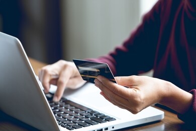 asian women who hold credit cards in their hands and are using laptop computers to buy products online