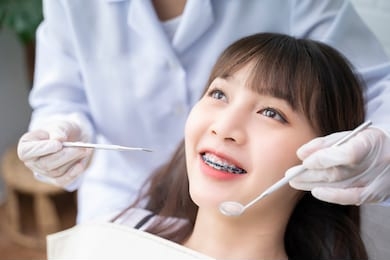 asian doctor dentist examine female patient with braces in a dental office, wearing gloves standing in clinic check close up young braces asian woman, beautiful asian girl smiles in dentistry.