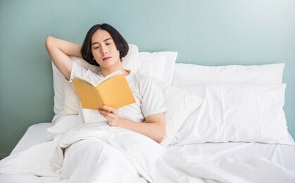 portrait of handsome young asian man with enjoy reading book in white bed room modern apartment. asian guy sleep resting, good night sleep, education sleepless concept panoramic banner