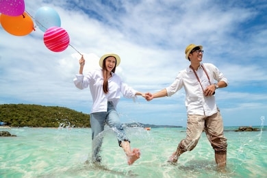 asian couple run and happy on pattaya beach with balloon on hand, thailand, this image can use for travel, love, sweet, summer and valentine concept
