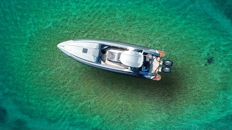 aerial top view luxury inflatable rib speed boat docked in mediterranean emerald bay with crystal clear sea